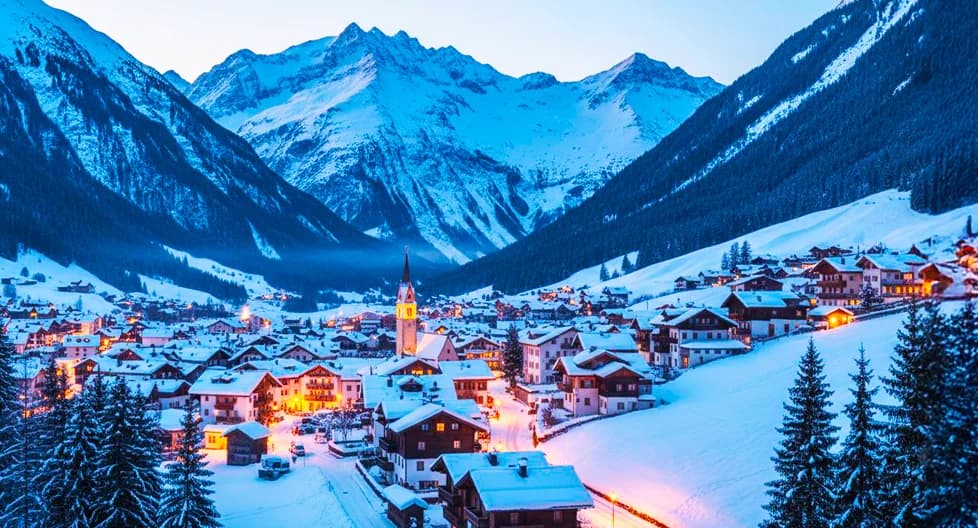 Austrian Alps ski resort village at dusk 2025 with traditional Tyrolean chalets and luxury ski hotels