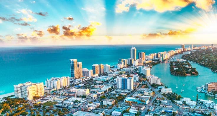 Stunning aerial view of Miami Beach skyline with turquoise ocean, white sandy beaches and luxury high-rise hotels at golden hour